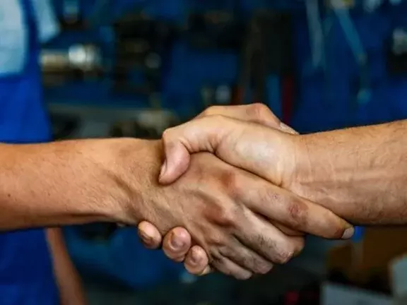 Dois trabalhadores apertam a mão um do outro