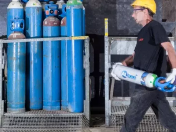 Trabalhador transporta um cilindro de CO₂ nas mãos