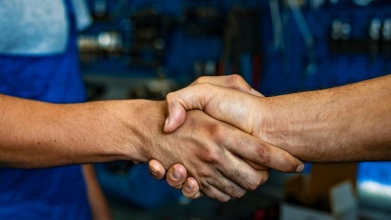 Dois trabalhadores apertam a mão um do outro