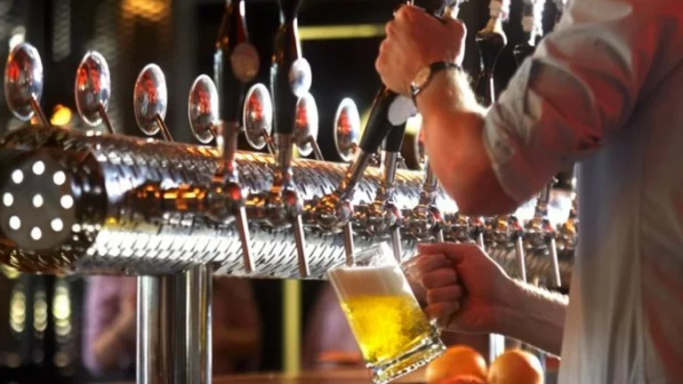 Barman opera uma chopeira para colocar chopp em uma caneca