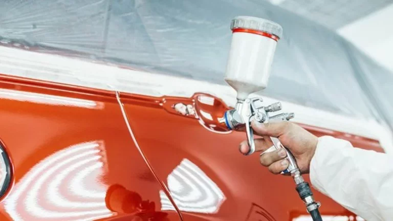 Profissional utiliza uma ferramenta de funilaria na lataria de um carro