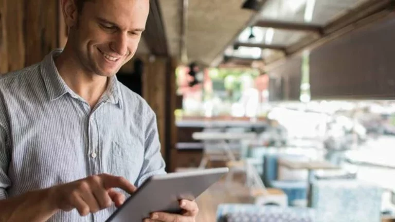 Homem trabalha com um tablet em mãos, em um restaurante