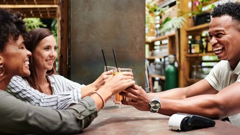 Pessoas alegres em um bar, com copos cheios de cerveja em suas mãos