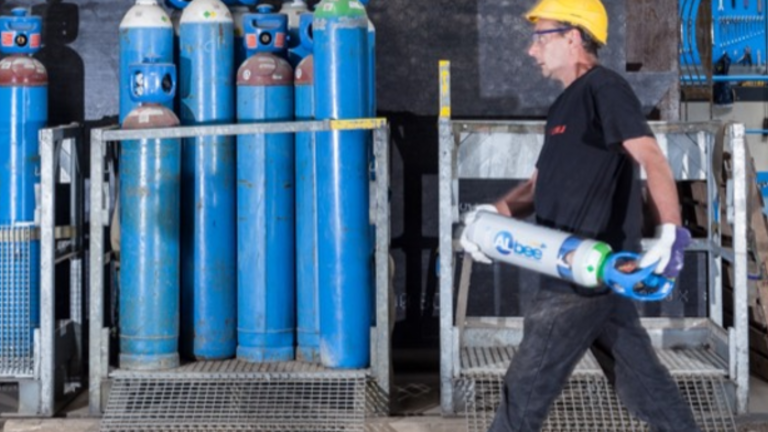 Trabalhador transporta um cilindro de CO₂ nas mãos