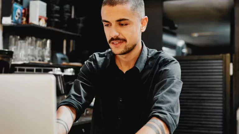 Homem trabalha em um computador em um bar