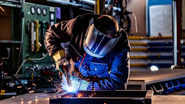 Homem com equipamentos corretos realizando soldagem 