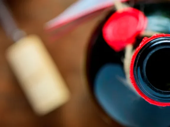 Garrafa de vinho aberta, com o abridor e a rolha postos à mesa