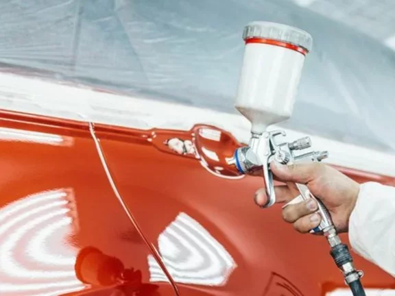 Profissional utiliza uma ferramenta de funilaria na lataria de um carro