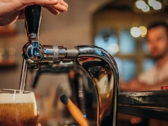 Barman opera uma chopeira para colocar chopp em uma caneca