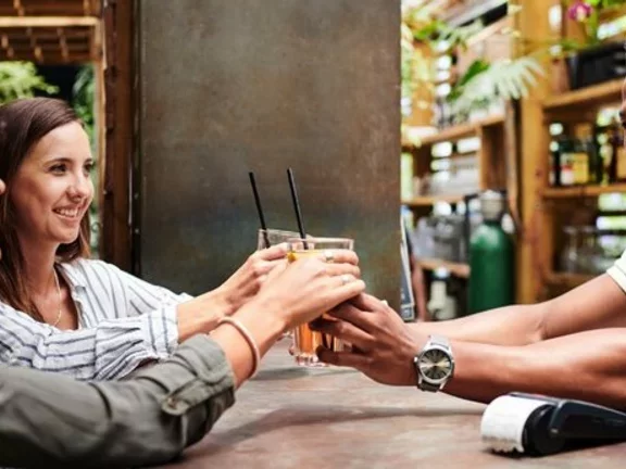 Pessoas alegres em um bar, com copos cheios de cerveja em suas mãos