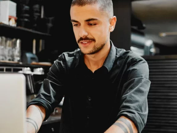 Homem trabalha em um computador em um bar