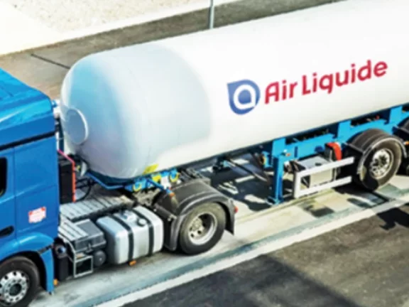 Caminhão da Air Liquide, a cabine é azul-piscina e o cilindro na parte de trás é branco com o logo da empresa