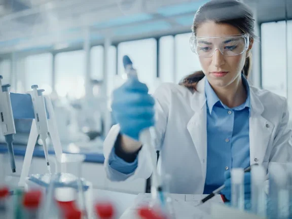 Cientista em laboratório realizando análise de qualidade com pipeta.