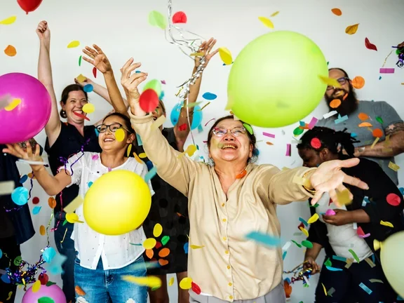 Grupo de pessoas felizes com balões e confetes coloridos 